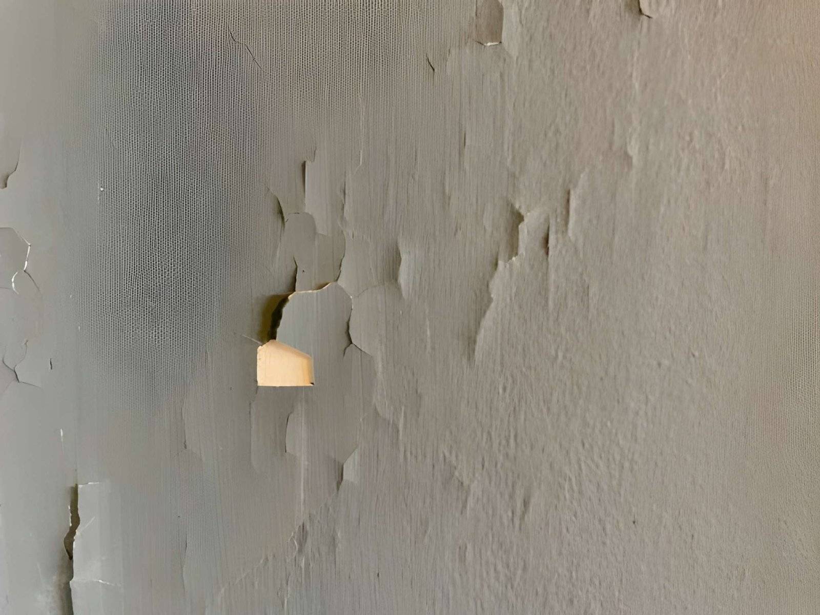 A wall with peeling paint and a small piece
