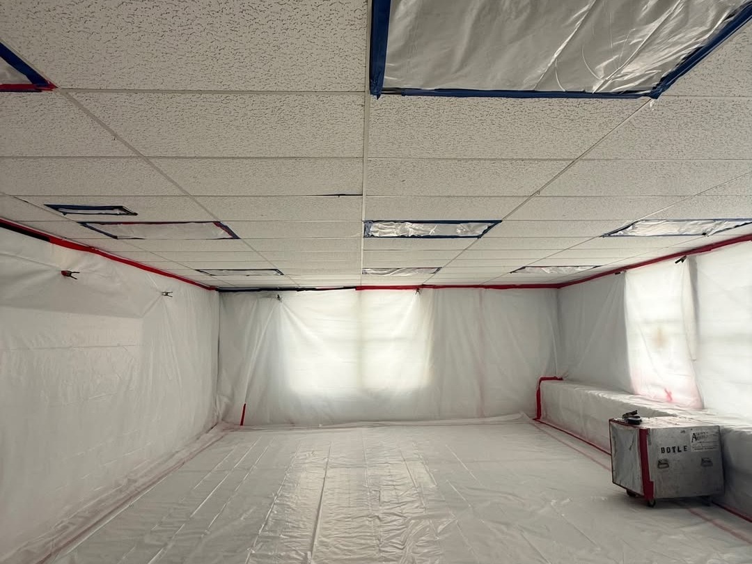 Room covered in white plastic sheeting for containment