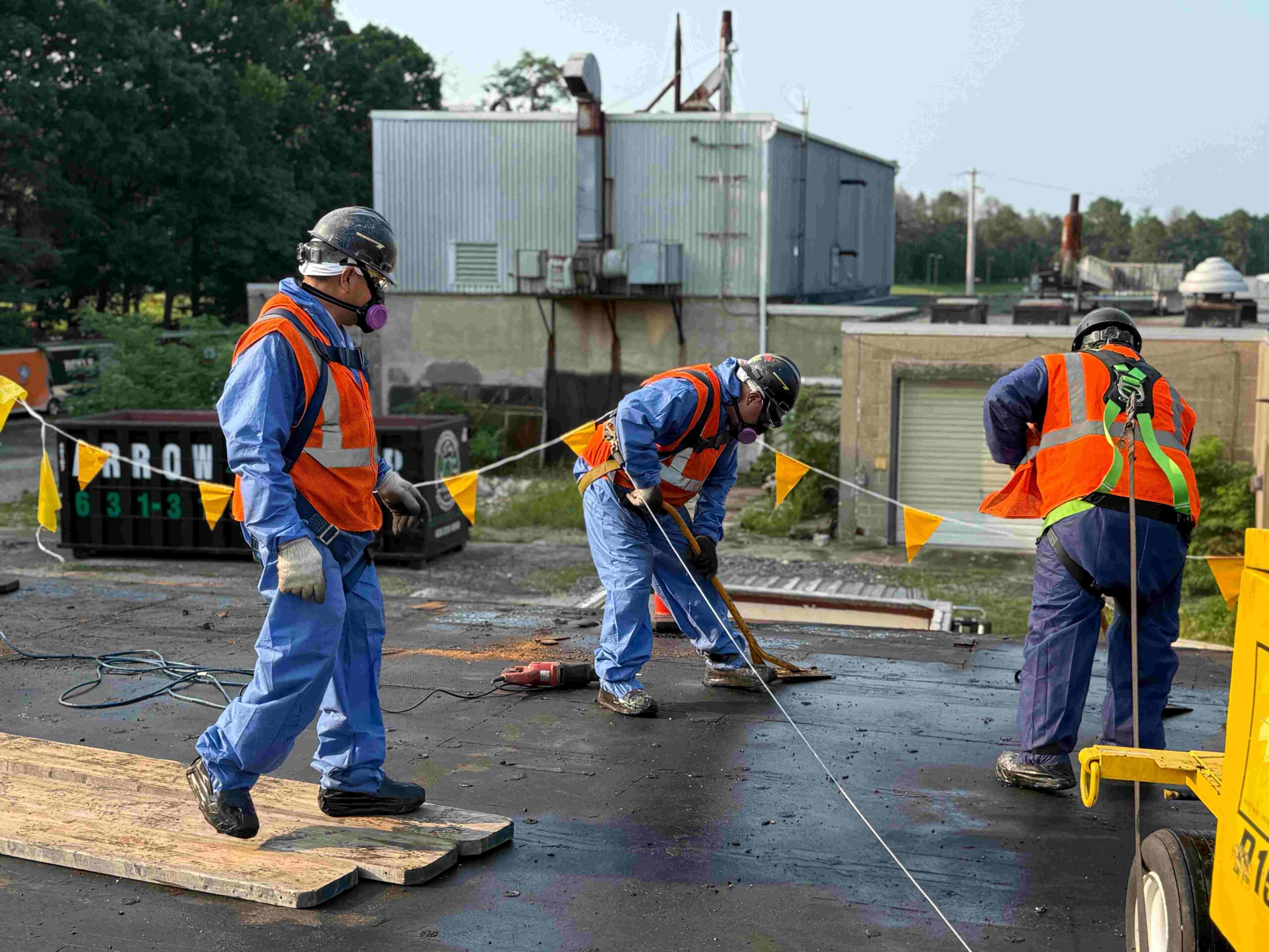 Workers in orange safety vests and blue coveralls