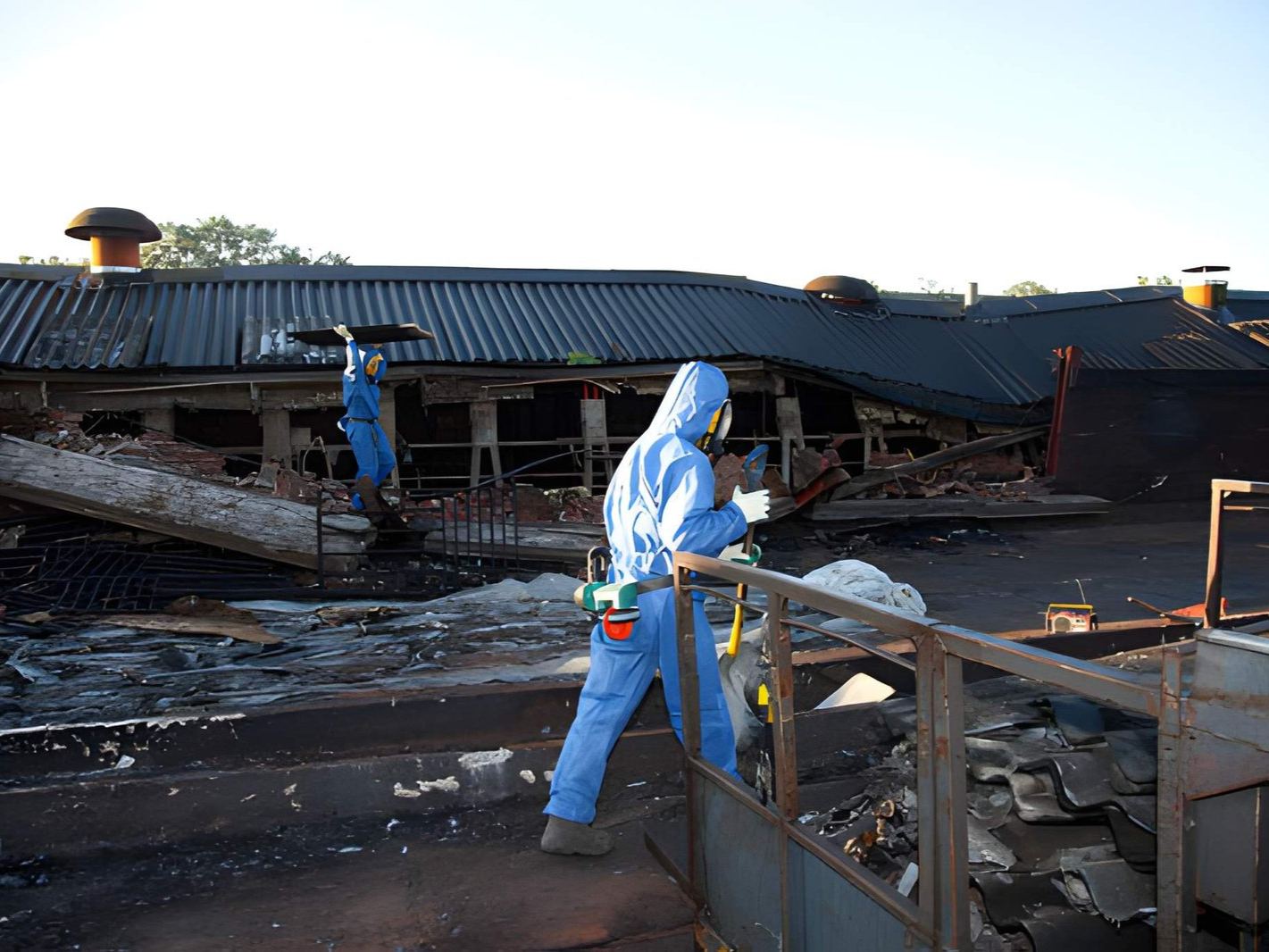 Workers in protective suits are removing asbestos from a damaged